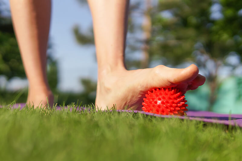 Faszienball unter einem Fuß auf einer Wiese