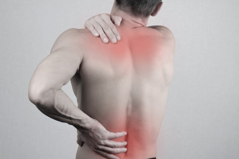 Mann hält Hände an Rücken und Schulter wegen Schmerzen