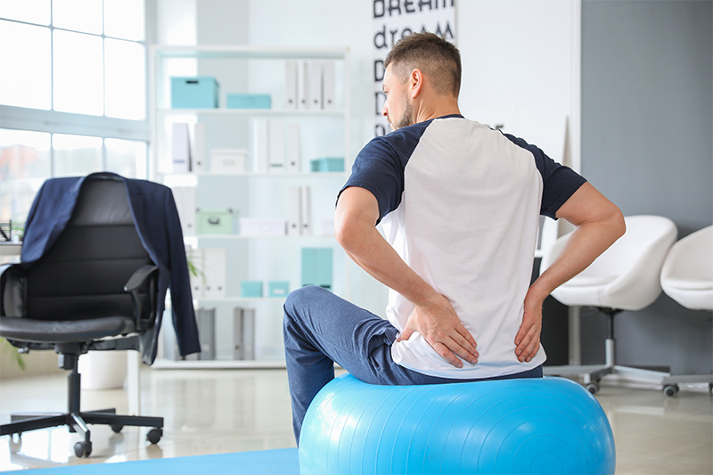 Mann sitzt auf einem Pezziball